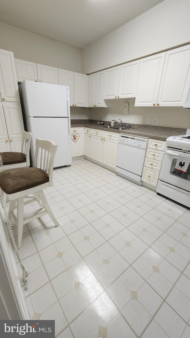 kitchen with light tile patterned floors, white appliances, and white cabinetry