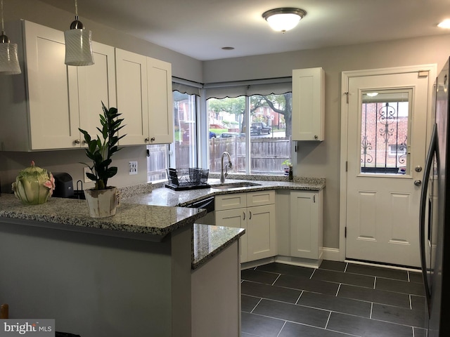 kitchen featuring white cabinetry, sink, hanging light fixtures, kitchen peninsula, and dark stone counters