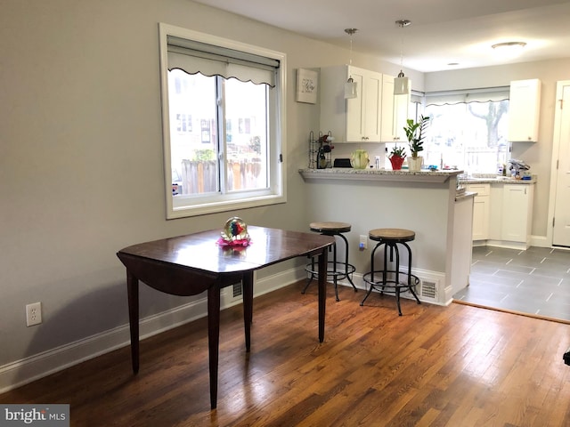 kitchen featuring light stone countertops, pendant lighting, white cabinetry, and plenty of natural light