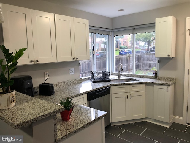 kitchen featuring light stone counters, dark tile patterned floors, sink, dishwasher, and white cabinets