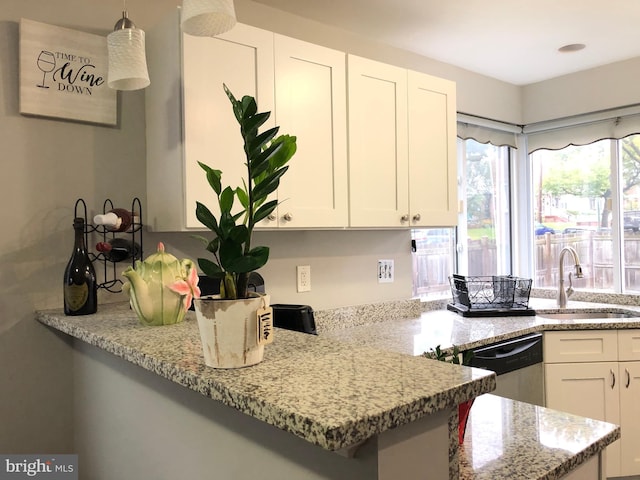 kitchen with kitchen peninsula, sink, dishwasher, white cabinetry, and hanging light fixtures