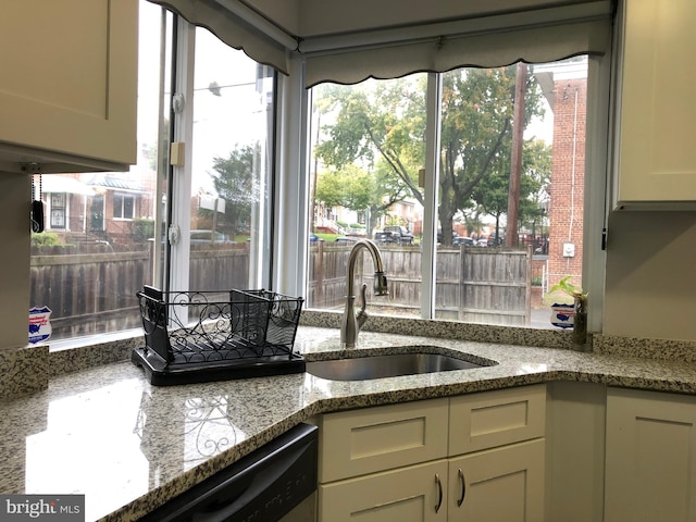 kitchen featuring light stone countertops, dishwasher, and sink