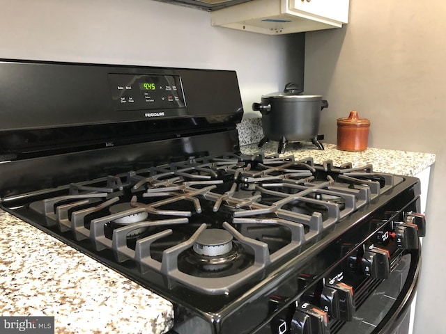 room details with black gas range and light stone counters