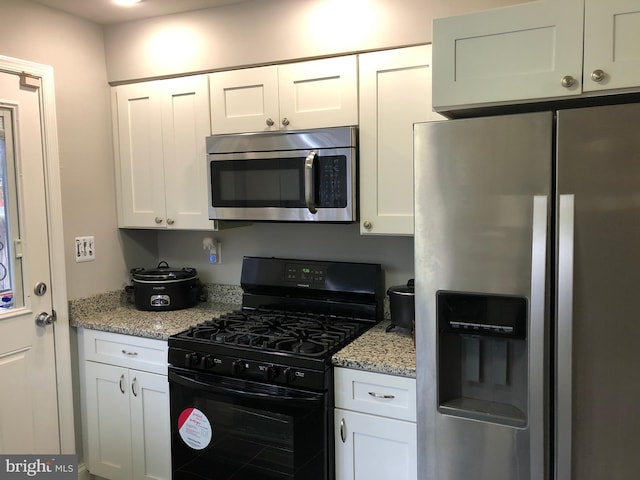 kitchen featuring light stone counters, white cabinets, and stainless steel appliances