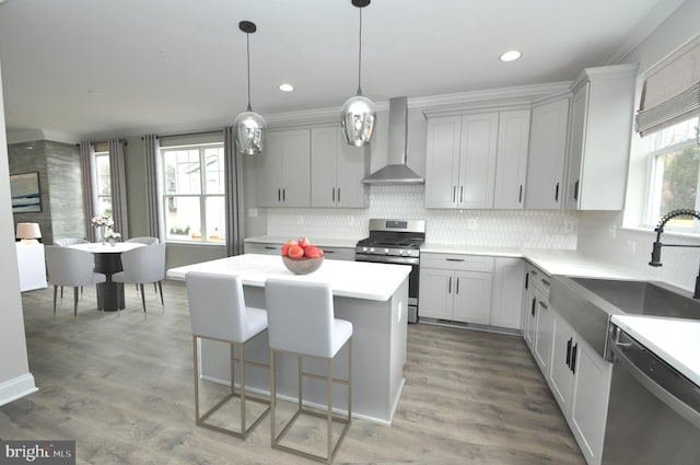 kitchen with gray cabinetry, sink, wall chimney exhaust hood, a kitchen island, and stainless steel appliances