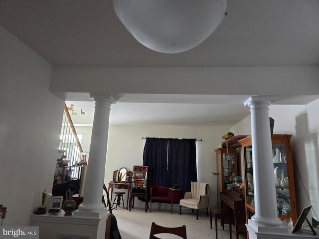 living area featuring ornate columns and carpet flooring