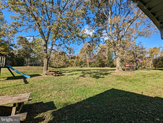 view of yard featuring a playground and a trampoline