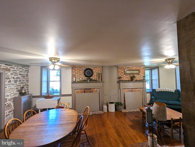 dining space with ceiling fan, wood-type flooring, a fireplace, and a wealth of natural light