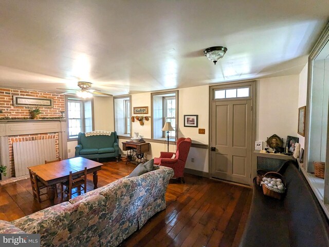 living room featuring a fireplace, dark wood-type flooring, and ceiling fan