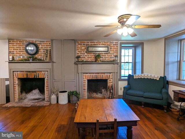 living room featuring ceiling fan, a brick fireplace, and dark hardwood / wood-style flooring