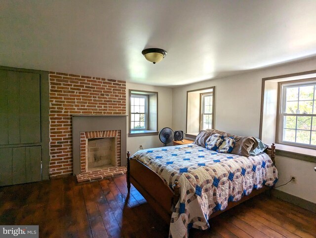 bedroom with dark wood-type flooring and a fireplace