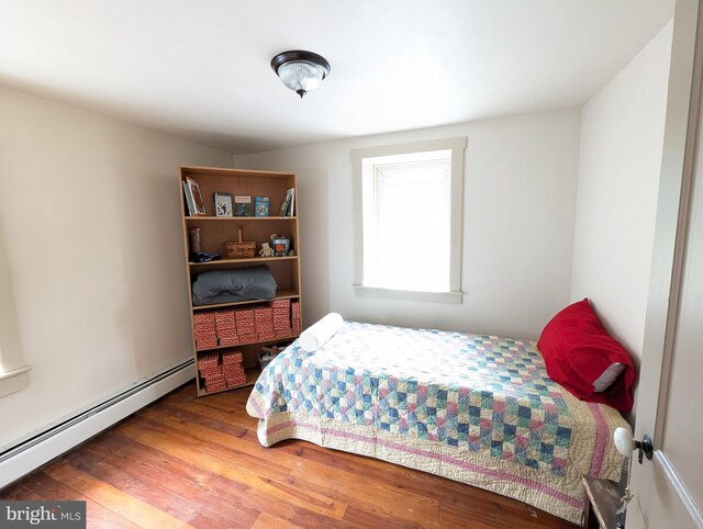 bedroom featuring baseboard heating and wood-type flooring