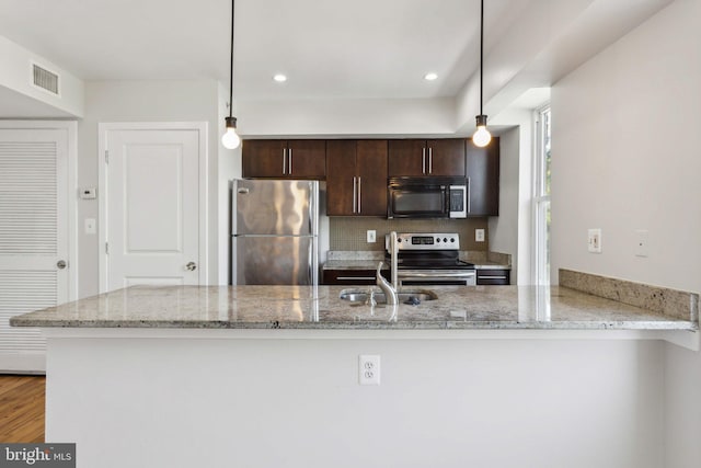 kitchen featuring kitchen peninsula, light stone counters, hanging light fixtures, and appliances with stainless steel finishes