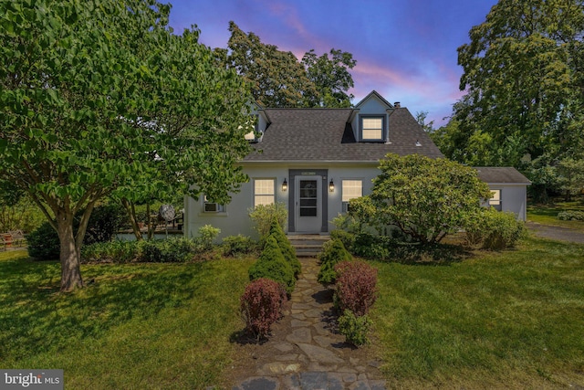 cape cod house featuring a lawn