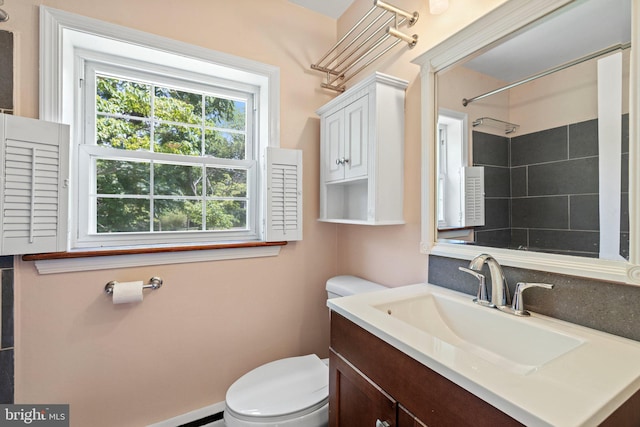 bathroom with vanity, toilet, and tiled shower