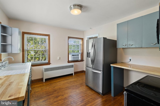 kitchen with radiator, sink, wooden counters, stainless steel refrigerator with ice dispenser, and stove