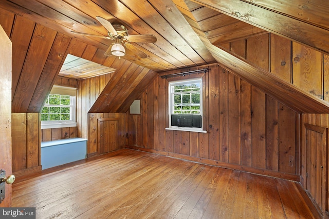 bonus room with plenty of natural light, light wood-type flooring, wooden walls, and lofted ceiling