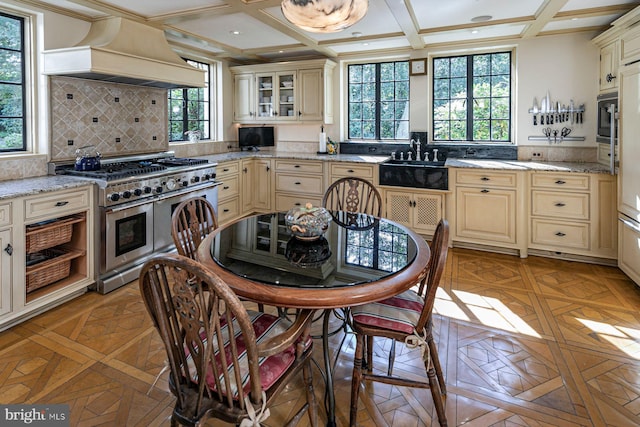 kitchen featuring plenty of natural light, premium range hood, range with two ovens, and cream cabinetry