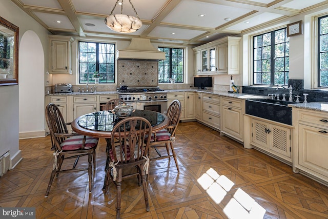 kitchen with custom exhaust hood, backsplash, decorative light fixtures, and light stone counters