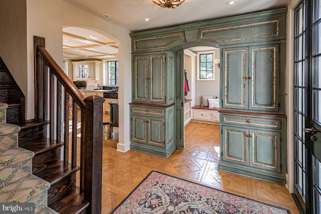 foyer with coffered ceiling, light parquet flooring, beam ceiling, and a healthy amount of sunlight