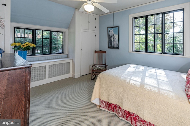 carpeted bedroom with radiator heating unit, vaulted ceiling, and ceiling fan