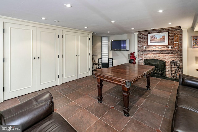 rec room featuring a brick fireplace and dark tile patterned floors