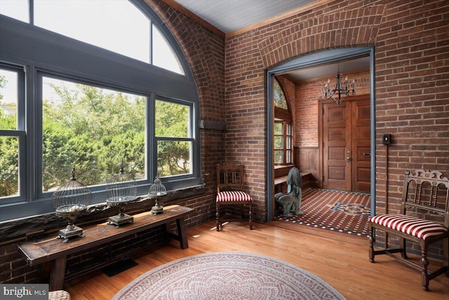 sitting room with brick wall, a chandelier, and light hardwood / wood-style floors