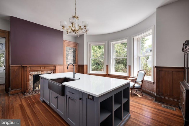 kitchen featuring sink, an inviting chandelier, a center island with sink, gray cabinets, and pendant lighting