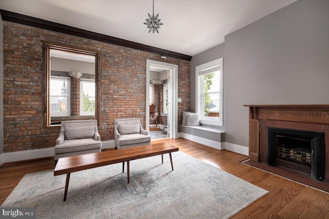 living room with hardwood / wood-style floors, brick wall, and ornamental molding