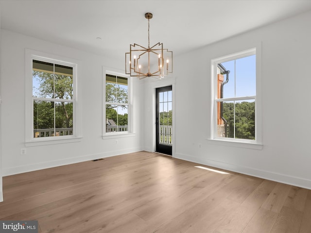 unfurnished dining area with a notable chandelier, plenty of natural light, and light hardwood / wood-style floors