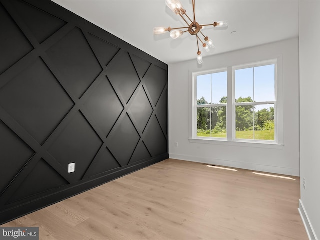 spare room featuring a chandelier and light hardwood / wood-style flooring