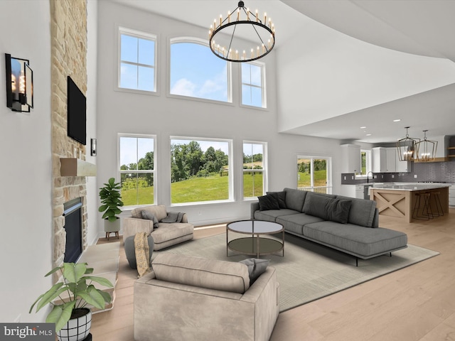 living room with light hardwood / wood-style flooring, a fireplace, a high ceiling, and a chandelier