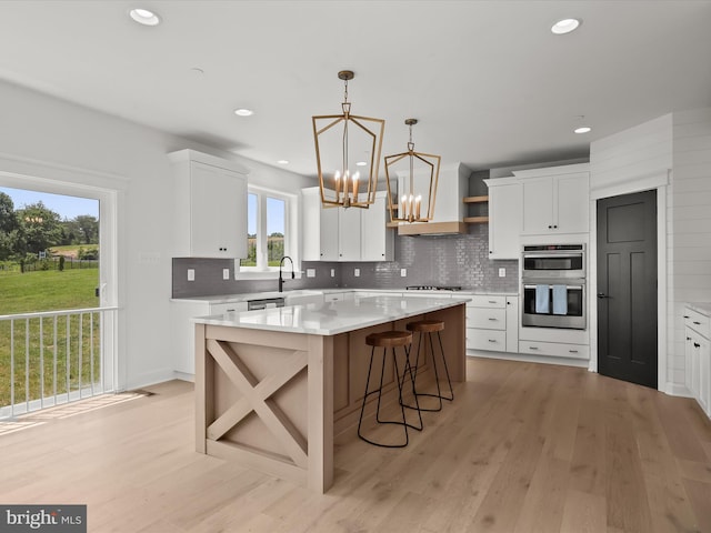 kitchen featuring a kitchen island, light wood-type flooring, white cabinetry, and double oven