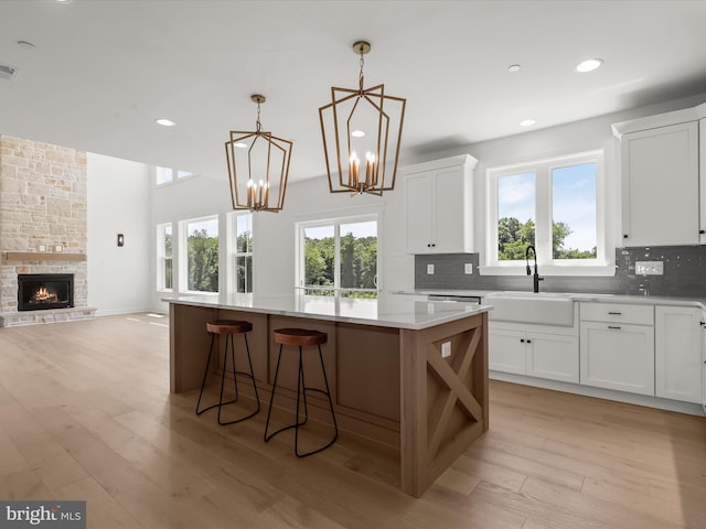 kitchen with white cabinetry, a center island, sink, decorative light fixtures, and a fireplace