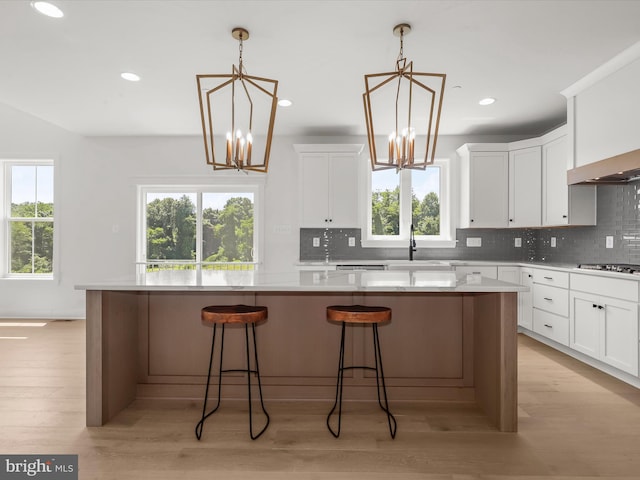 kitchen with white cabinets, a kitchen island, pendant lighting, and an inviting chandelier