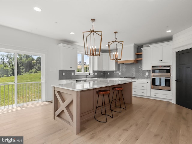 kitchen with a center island, stainless steel double oven, gas cooktop, pendant lighting, and white cabinets