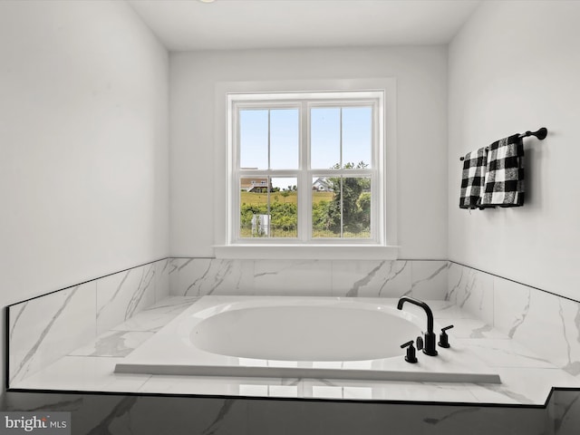 bathroom with a healthy amount of sunlight and tiled tub