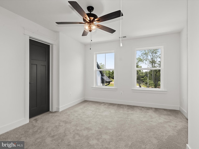 empty room featuring ceiling fan and light colored carpet