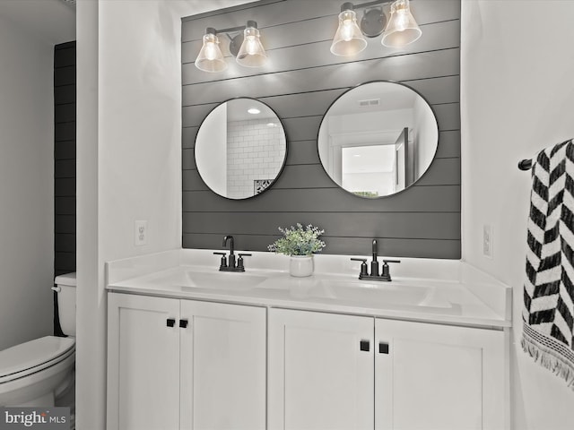 bathroom featuring vanity, toilet, and wooden walls