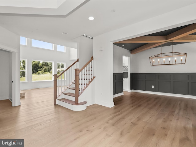 interior space with vaulted ceiling with beams, an inviting chandelier, and hardwood / wood-style flooring