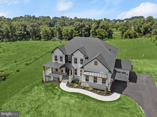 view of front of home featuring covered porch, a garage, and a front lawn