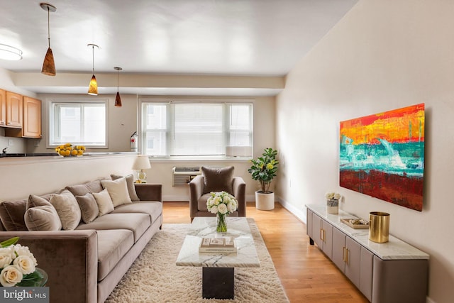 living room featuring light hardwood / wood-style floors, a healthy amount of sunlight, and an AC wall unit