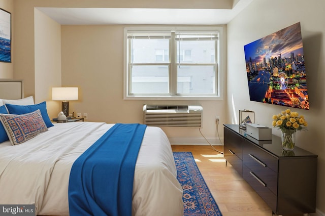 bedroom with light hardwood / wood-style flooring, multiple windows, and a wall unit AC