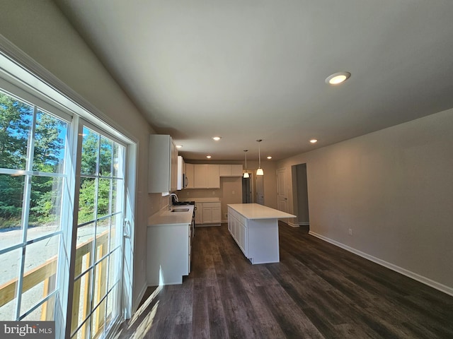 kitchen featuring a center island, sink, hanging light fixtures, dark hardwood / wood-style floors, and white cabinetry