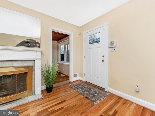 foyer entrance with a fireplace and light hardwood / wood-style flooring