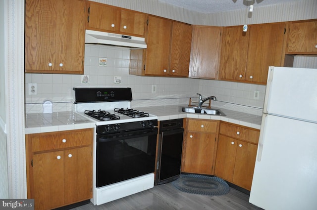 kitchen with backsplash, white appliances, sink, dark hardwood / wood-style floors, and tile counters