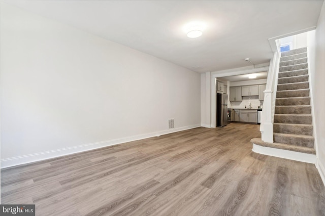 unfurnished living room featuring light wood-type flooring and sink