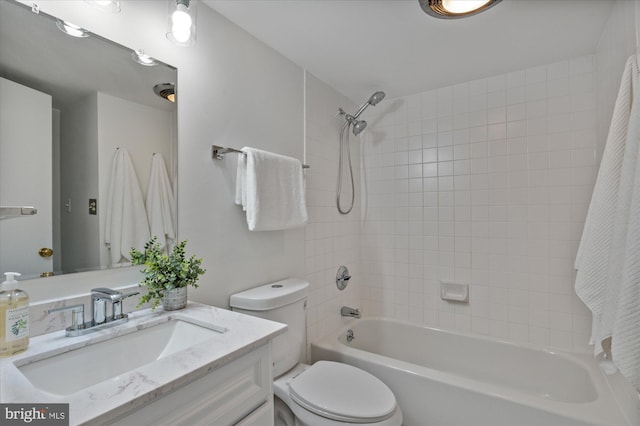 full bathroom featuring tiled shower / bath, vanity, and toilet