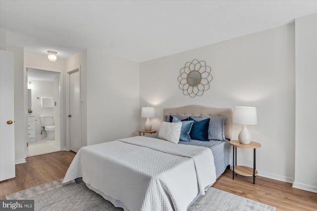 bedroom featuring ensuite bath and hardwood / wood-style floors