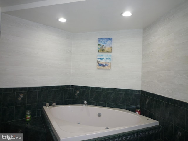 bathroom with tile walls and tiled tub